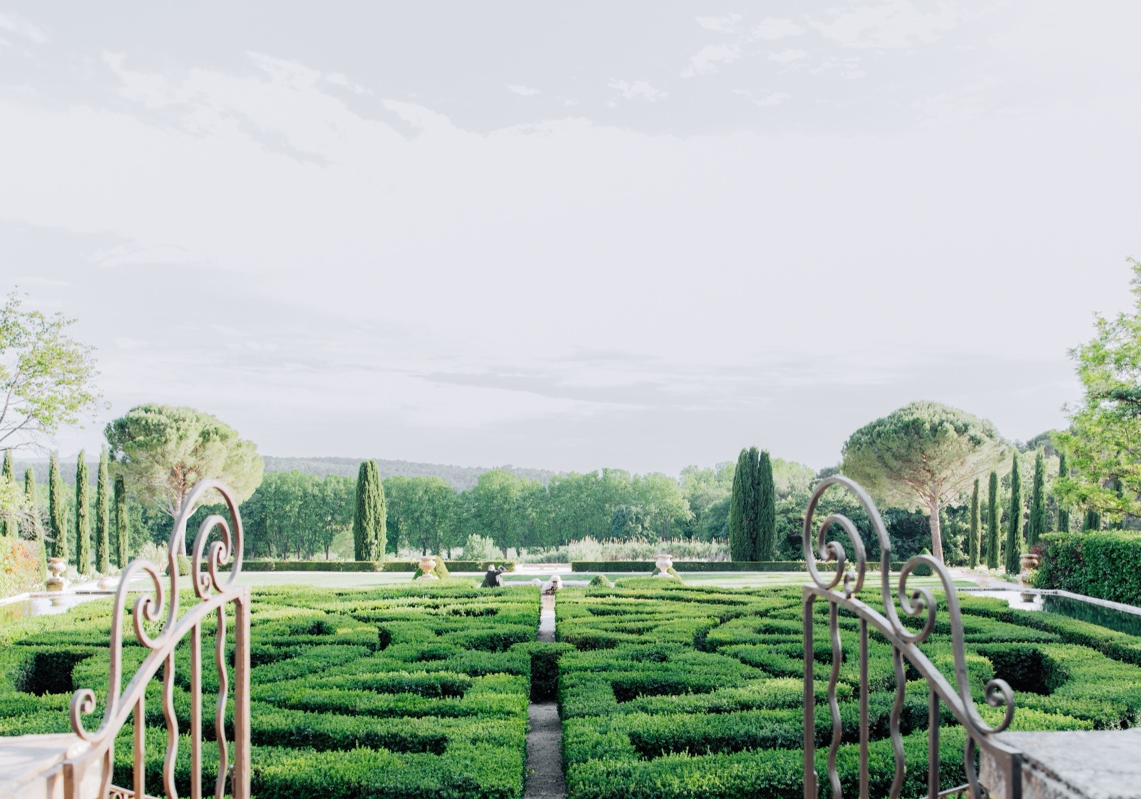 A formal French garden seen through wrought-iron gates